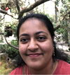 A young lady smiling in front of a forest stream