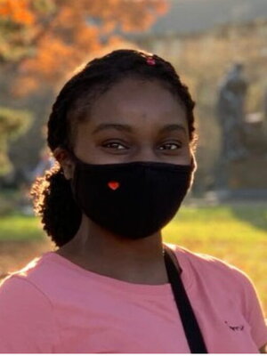 A young lady smiling with a mask on , in front of Aluma Molter