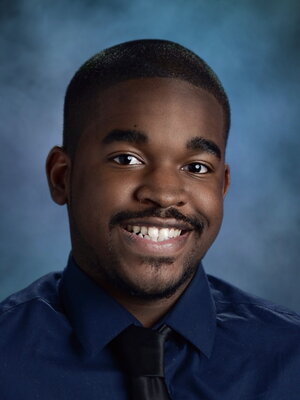 A young man smiling in front of blue black drop