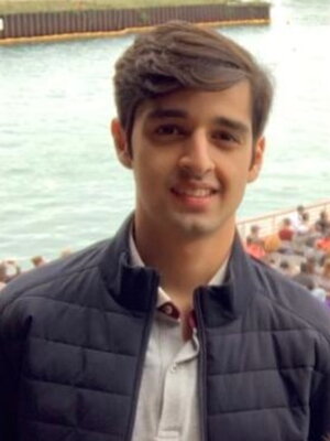 A young man smiling in front of a boat of ppl on a river