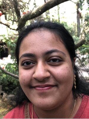 A young lady smiling in front of a forest stream