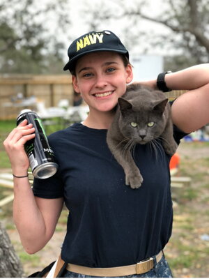 A female smiling while her cat is on her shoulders