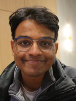 Aditya Ramesh Smiling at the camera from inside a classroom