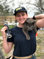 A female smiling while her cat is on her shoulders